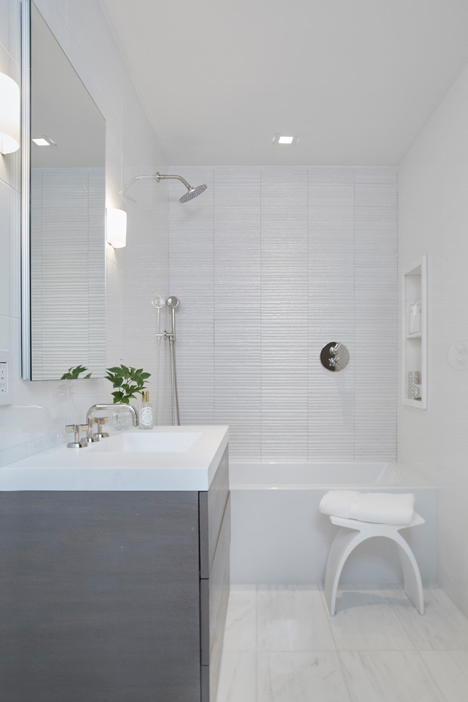 На фото: ванная комната среднего размера в стиле модернизм с плоскими фасадами, серыми фасадами, ванной в нише, душем над ванной, белыми стенами, полом из керамогранита, душевой кабиной, монолитной раковиной, столешницей из искусственного кварца, белым полом, шторкой для ванной и белой столешницей