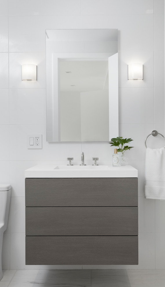 Idée de décoration pour une salle d'eau minimaliste de taille moyenne avec un placard à porte plane, des portes de placard grises, une baignoire en alcôve, un combiné douche/baignoire, un carrelage blanc, des carreaux de céramique, un mur blanc, un sol en carrelage de porcelaine, un lavabo intégré, un plan de toilette en quartz modifié, un sol blanc, une cabine de douche avec un rideau et un plan de toilette blanc.