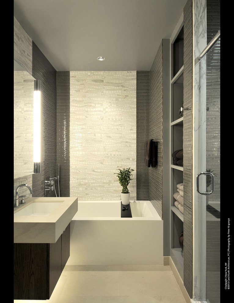 Foto di una stanza da bagno minimalista con lavabo sospeso, ante lisce, ante in legno bruno, vasca da incasso, doccia alcova, piastrelle grigie, piastrelle di vetro e pareti grigie
