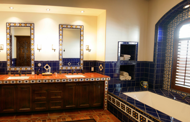 Стильный дизайн: большая главная ванная комната в средиземноморском стиле с полновстраиваемой ванной, синей плиткой, керамической плиткой, бежевыми стенами, полом из терракотовой плитки, врезной раковиной, красным полом, фасадами с выступающей филенкой, темными деревянными фасадами, столешницей из плитки и оранжевой столешницей - последний тренд