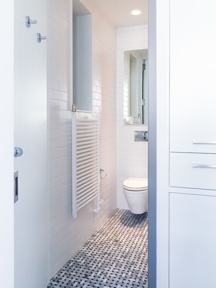 Foto di una stanza da bagno padronale industriale con vasca con piedi a zampa di leone, WC sospeso, piastrelle bianche, piastrelle in ceramica e pavimento con piastrelle a mosaico