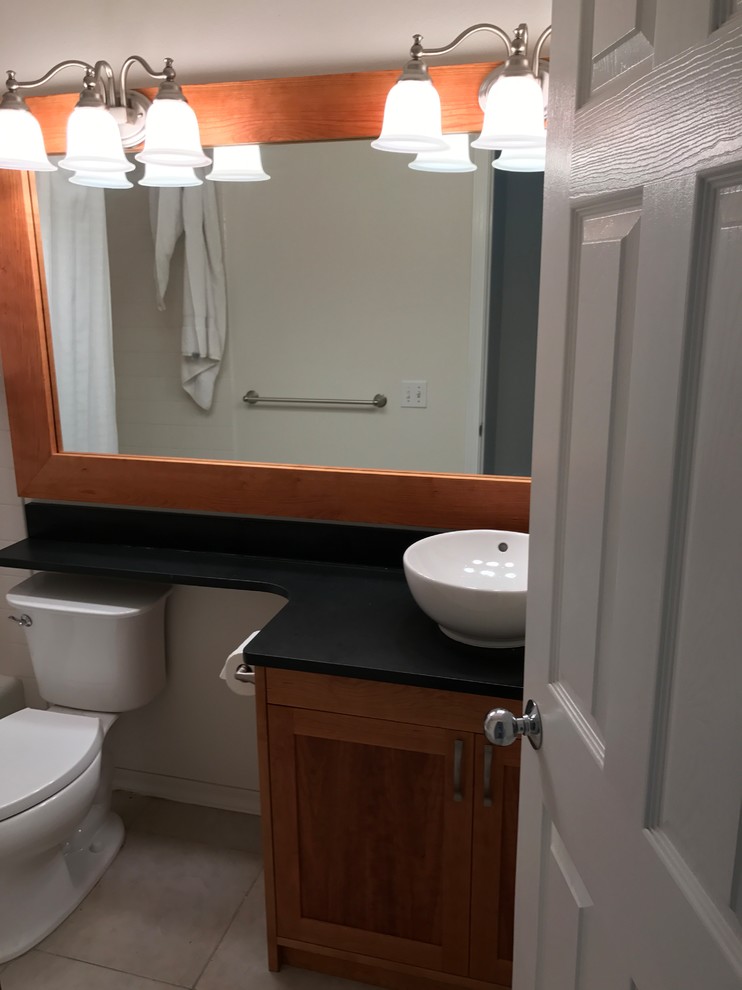 Exemple d'une salle d'eau craftsman en bois brun de taille moyenne avec un placard à porte shaker, un mur beige, un sol en carrelage de céramique, une vasque, un plan de toilette en surface solide et un sol beige.