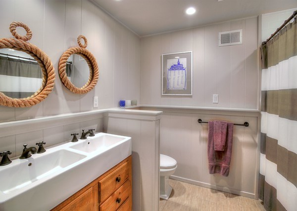 Photo of a medium sized nautical shower room bathroom in Seattle with flat-panel cabinets, light wood cabinets, a corner bath, a walk-in shower, a one-piece toilet, stone tiles, white walls, ceramic flooring, a trough sink and wooden worktops.