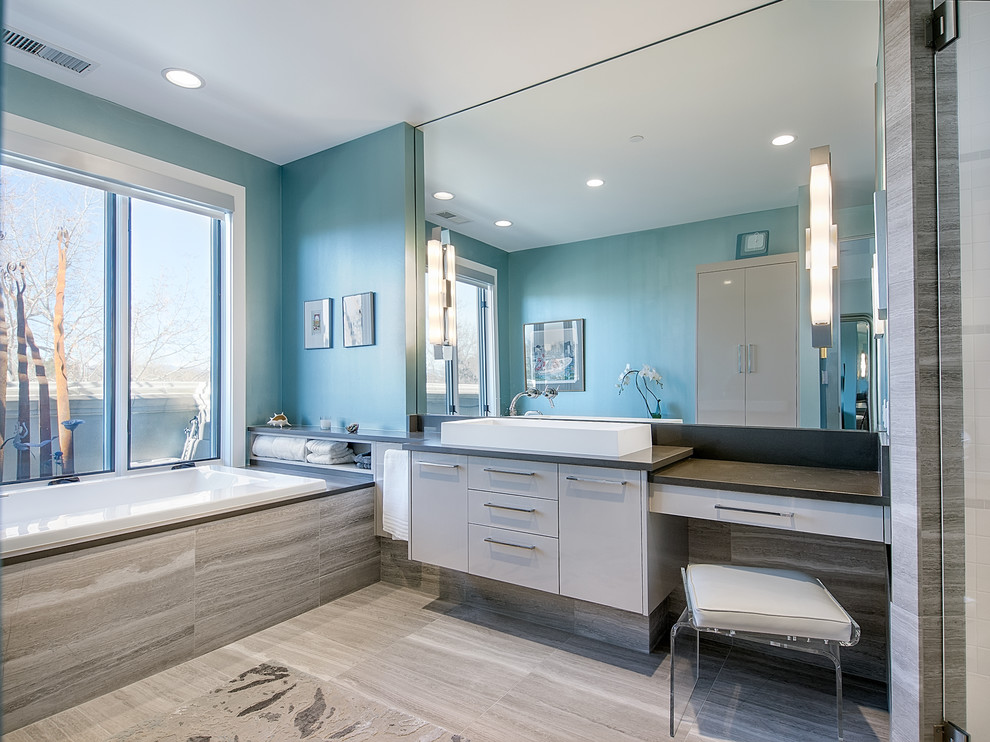На фото: ванная комната в современном стиле с настольной раковиной, серыми фасадами, столешницей из искусственного кварца, накладной ванной, угловым душем, унитазом-моноблоком, серой плиткой, каменной плиткой и серой столешницей с