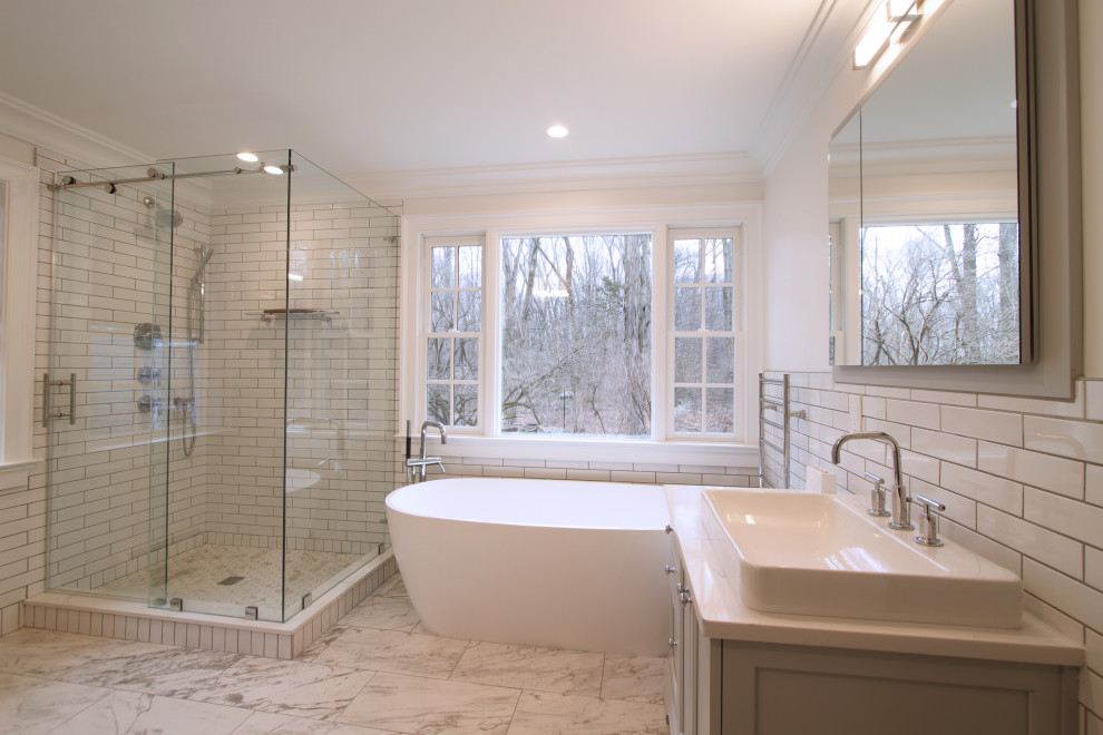 Foto på ett mellanstort vintage beige en-suite badrum, med skåp i shakerstil, vita skåp, ett fristående badkar, en hörndusch, en bidé, vit kakel, keramikplattor, vita väggar, klinkergolv i porslin, ett fristående handfat, bänkskiva i kvarts, grått golv och dusch med skjutdörr