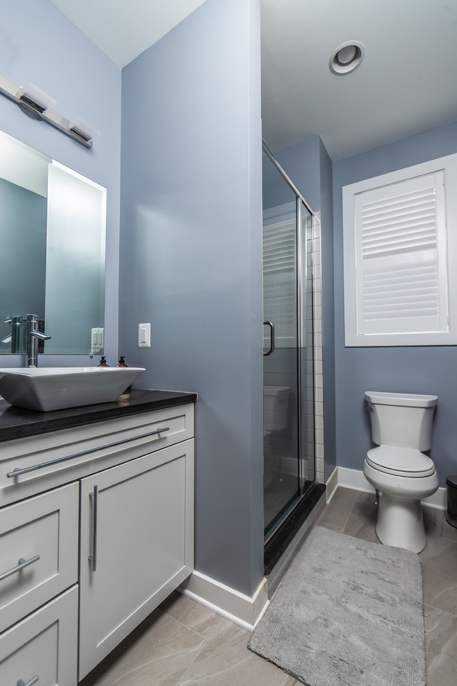 Bathroom - large contemporary 3/4 multicolored tile porcelain tile and beige floor bathroom idea in Baltimore with shaker cabinets, white cabinets, a two-piece toilet, blue walls, a vessel sink, solid surface countertops, a hinged shower door and black countertops