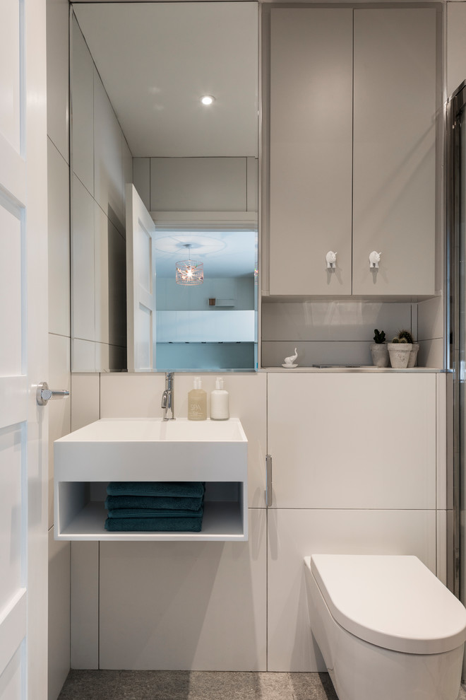 Design ideas for a small contemporary ensuite bathroom in Cheshire with flat-panel cabinets, grey cabinets, a built-in shower, a wall mounted toilet, white tiles, ceramic tiles, a wall-mounted sink, a sliding door, white walls and grey floors.