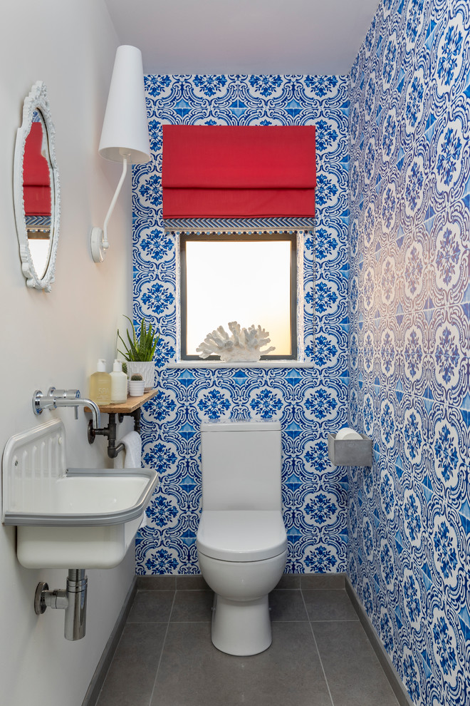 Ejemplo de cuarto de baño bohemio pequeño con sanitario de una pieza, paredes azules, lavabo suspendido, baldosas y/o azulejos azules, baldosas y/o azulejos blancos y suelo gris