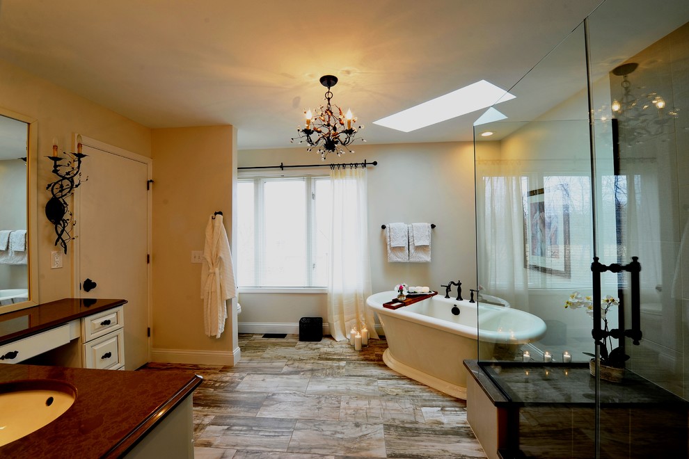 На фото: большая главная ванная комната в классическом стиле с фасадами с выступающей филенкой, бежевыми фасадами, отдельно стоящей ванной, открытым душем, серой плиткой, керамической плиткой, полом из керамической плитки, врезной раковиной, столешницей из искусственного кварца, бежевыми стенами, коричневым полом, душем с распашными дверями и коричневой столешницей