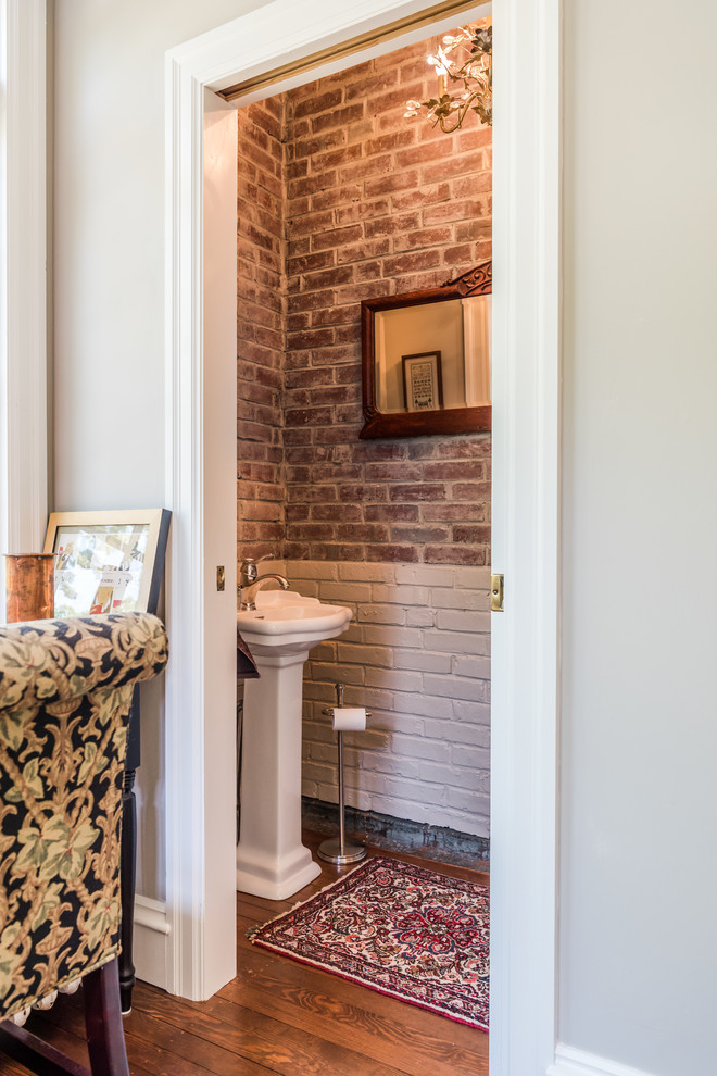 Aménagement d'une petite salle d'eau classique avec WC à poser, un mur rouge, un sol en bois brun et un plan vasque.