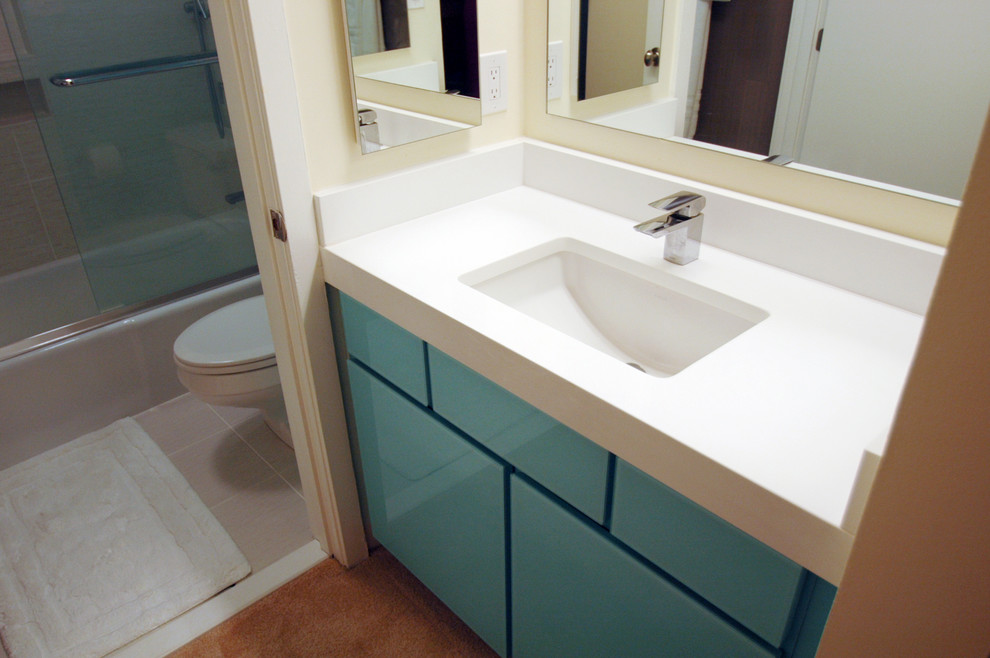 Idéer för små funkis en-suite badrum, med ett undermonterad handfat, luckor med glaspanel, blå skåp, bänkskiva i kvartsit, en dusch/badkar-kombination, en toalettstol med separat cisternkåpa, grå kakel, porslinskakel, blå väggar och klinkergolv i porslin