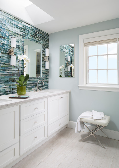 Bright bathroom with white shaker-style cabinets, quartz countertop, modern chrome fixtures, and blue glass mosaic accent wall.