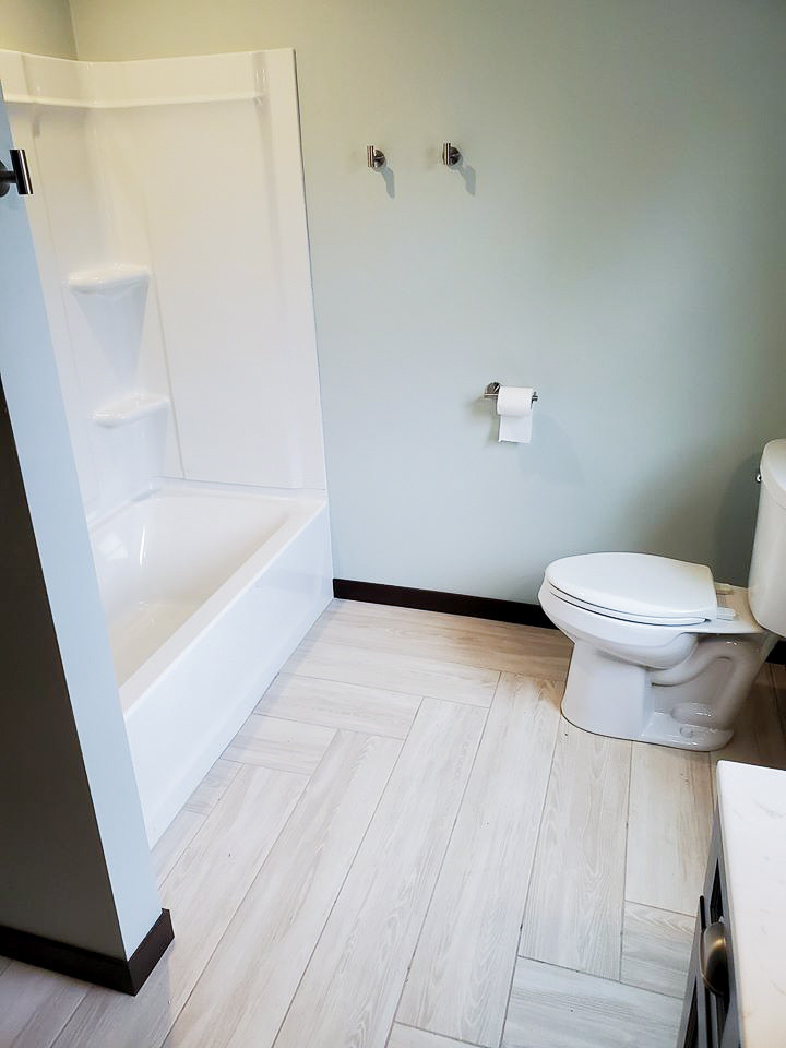 Стильный дизайн: ванная комната среднего размера в стиле модернизм с плоскими фасадами, темными деревянными фасадами, душем над ванной, раздельным унитазом, синими стенами, полом из винила, монолитной раковиной, столешницей из искусственного камня, серым полом, шторкой для ванной, белой столешницей, тумбой под одну раковину и встроенной тумбой - последний тренд