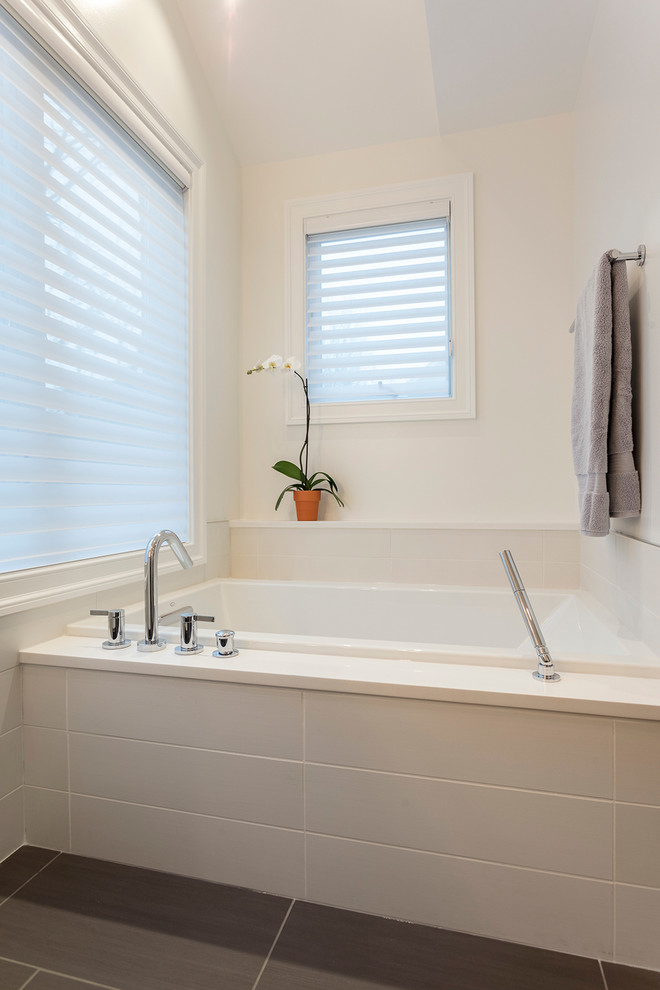 Modern inredning av ett stort en-suite badrum, med släta luckor, vita skåp, ett platsbyggt badkar, en dusch i en alkov, en vägghängd toalettstol, vit kakel, keramikplattor, vita väggar, klinkergolv i porslin och ett integrerad handfat