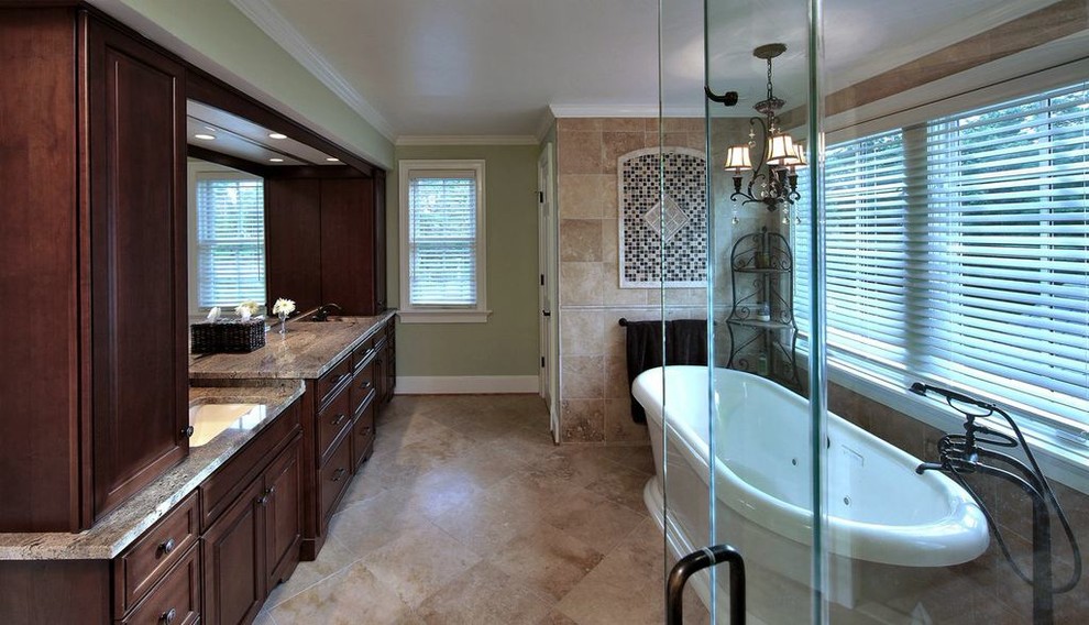 Photo of a large mediterranean ensuite bathroom in DC Metro with a submerged sink, raised-panel cabinets, dark wood cabinets, granite worktops, a freestanding bath, a corner shower, a two-piece toilet, beige tiles, stone slabs, green walls and marble flooring.