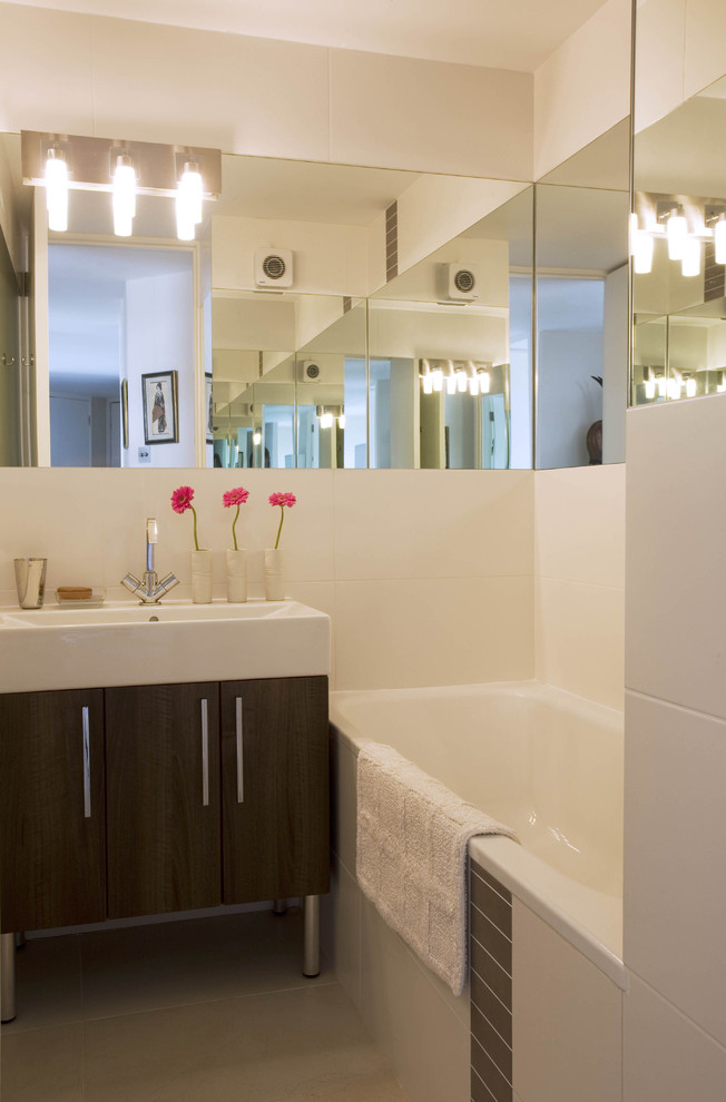 Modernes Badezimmer mit Aufsatzwaschbecken, flächenbündigen Schrankfronten, dunklen Holzschränken, Badewanne in Nische und weißen Fliesen in London
