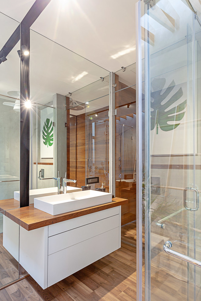 На фото: ванная комната в современном стиле с плоскими фасадами, белыми фасадами, настольной раковиной, столешницей из дерева, коричневым полом и коричневой столешницей с