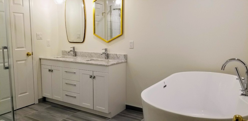 Cette photo montre une salle de bain principale tendance de taille moyenne avec un placard avec porte à panneau encastré, des portes de placard blanches, une baignoire indépendante, une douche d'angle, un sol en carrelage de porcelaine, un sol gris, un plan de toilette gris, meuble double vasque et meuble-lavabo encastré.