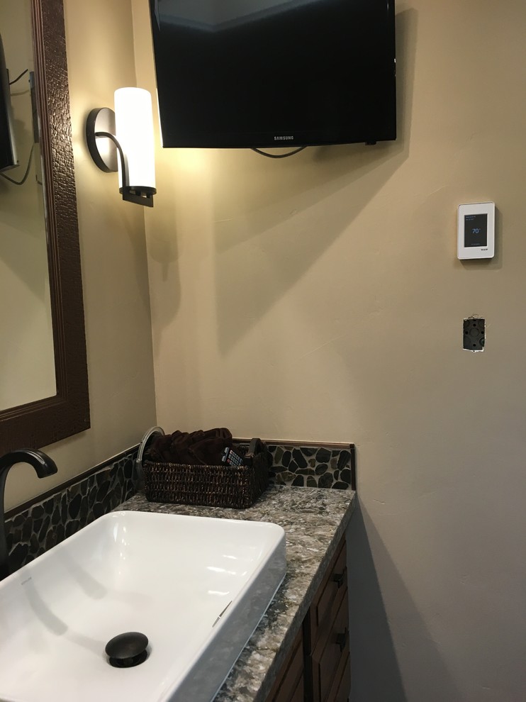 Immagine di una stanza da bagno contemporanea di medie dimensioni con WC a due pezzi, piastrelle nere, piastrelle di ciottoli, pareti beige, pavimento in gres porcellanato, ante in legno scuro, lavabo rettangolare e top in quarzo composito