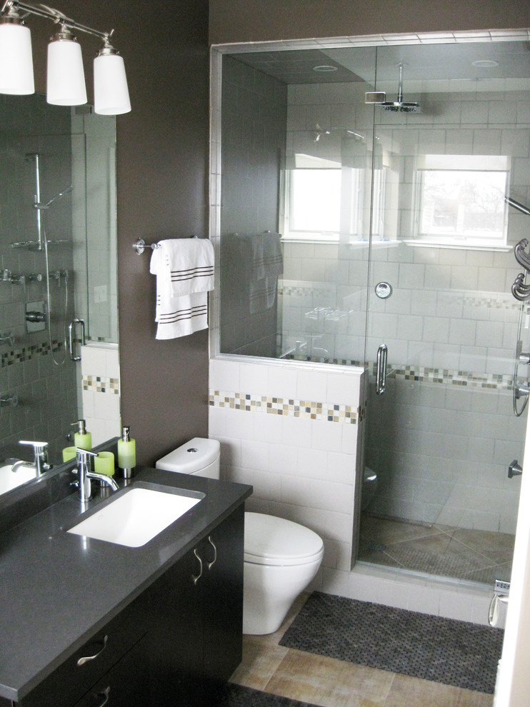 This is an example of a medium sized modern ensuite bathroom in Chicago with flat-panel cabinets, dark wood cabinets, solid surface worktops, a corner shower, a one-piece toilet, white tiles, porcelain tiles, brown walls and light hardwood flooring.