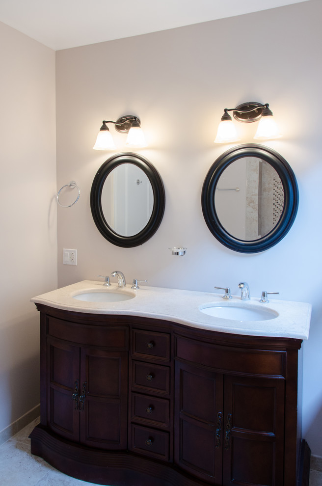 Immagine di una stanza da bagno tradizionale con lavabo da incasso, ante con bugna sagomata, ante in legno bruno e pareti bianche