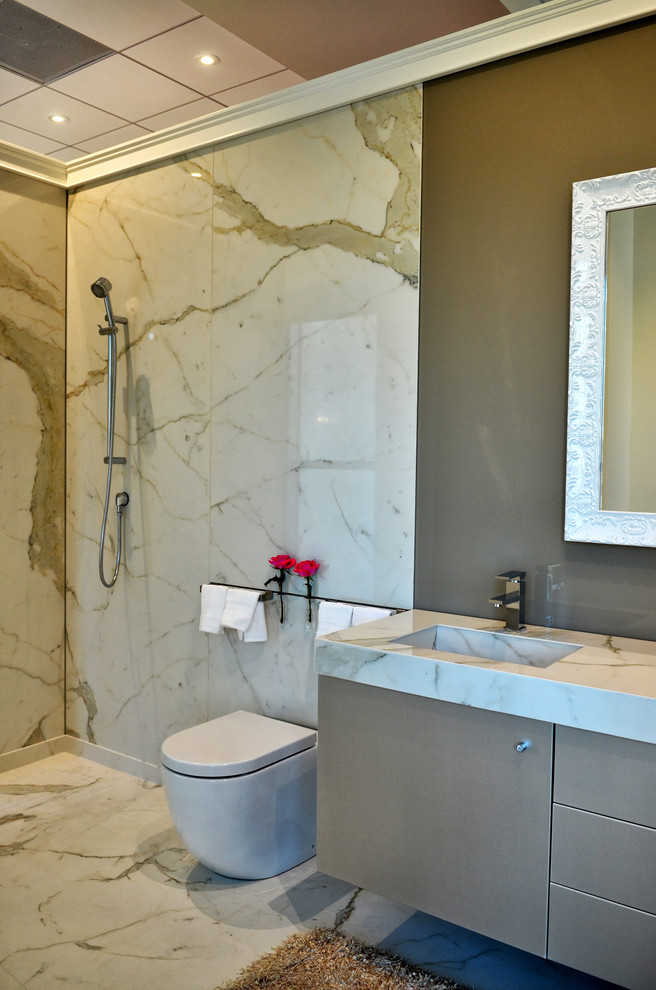 Inredning av ett modernt en-suite badrum, med grå skåp, en kantlös dusch, flerfärgad kakel, glasskiva, ett integrerad handfat, bänkskiva i glas och med dusch som är öppen