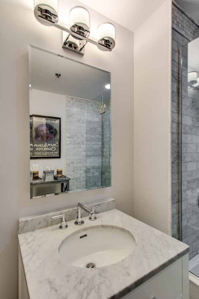 Exempel på ett mellanstort modernt badrum, med ett undermonterad handfat, släta luckor, vita skåp, marmorbänkskiva, ett badkar i en alkov, en dusch/badkar-kombination, en toalettstol med separat cisternkåpa, grå kakel, stenhäll, grå väggar och marmorgolv