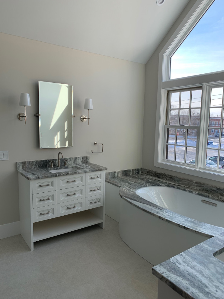 Large traditional ensuite bathroom in Chicago with freestanding cabinets, white cabinets, a submerged bath, a walk-in shower, a one-piece toilet, grey tiles, pebble tiles, grey walls, ceramic flooring, a submerged sink, quartz worktops, grey floors, a hinged door, grey worktops, an enclosed toilet, a single sink, a freestanding vanity unit and a vaulted ceiling.