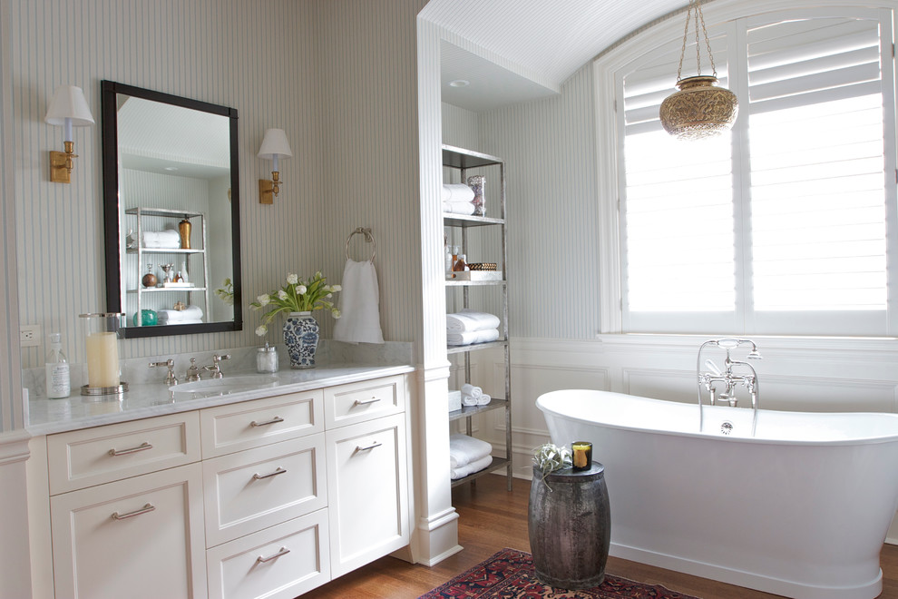 Idéer för ett mellanstort klassiskt en-suite badrum, med luckor med infälld panel, vita skåp, ett fristående badkar, ljust trägolv, ett undermonterad handfat och marmorbänkskiva