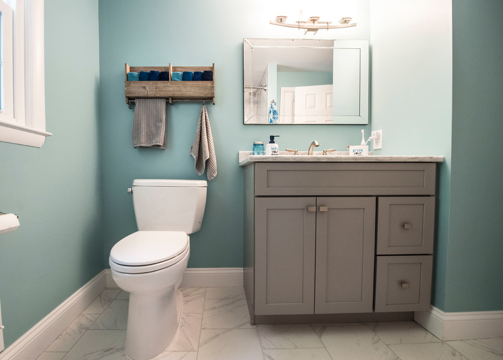 Cette image montre une salle de bain style shabby chic de taille moyenne pour enfant avec un placard à porte shaker, des portes de placard grises, une baignoire en alcôve, un combiné douche/baignoire, WC séparés, un carrelage gris, des carreaux de céramique, un mur bleu, un sol en carrelage de porcelaine, un lavabo encastré, un plan de toilette en quartz, un sol blanc et une cabine de douche avec un rideau.