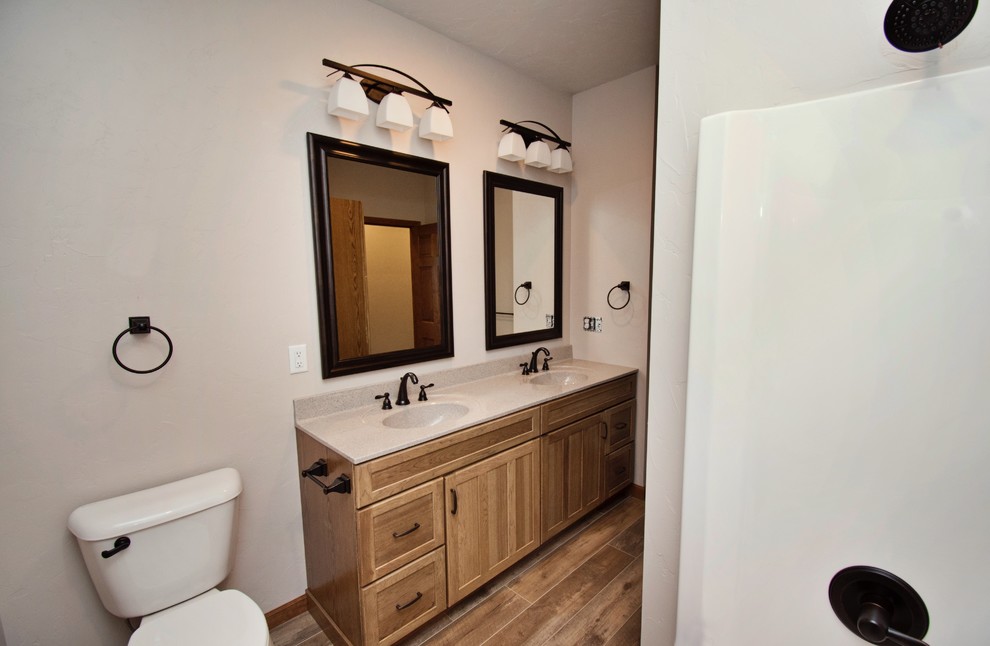 Design ideas for a medium sized country family bathroom in Other with recessed-panel cabinets, medium wood cabinets, an alcove bath, a shower/bath combination, a two-piece toilet, white walls, medium hardwood flooring, an integrated sink, laminate worktops, brown floors, a shower curtain and beige worktops.