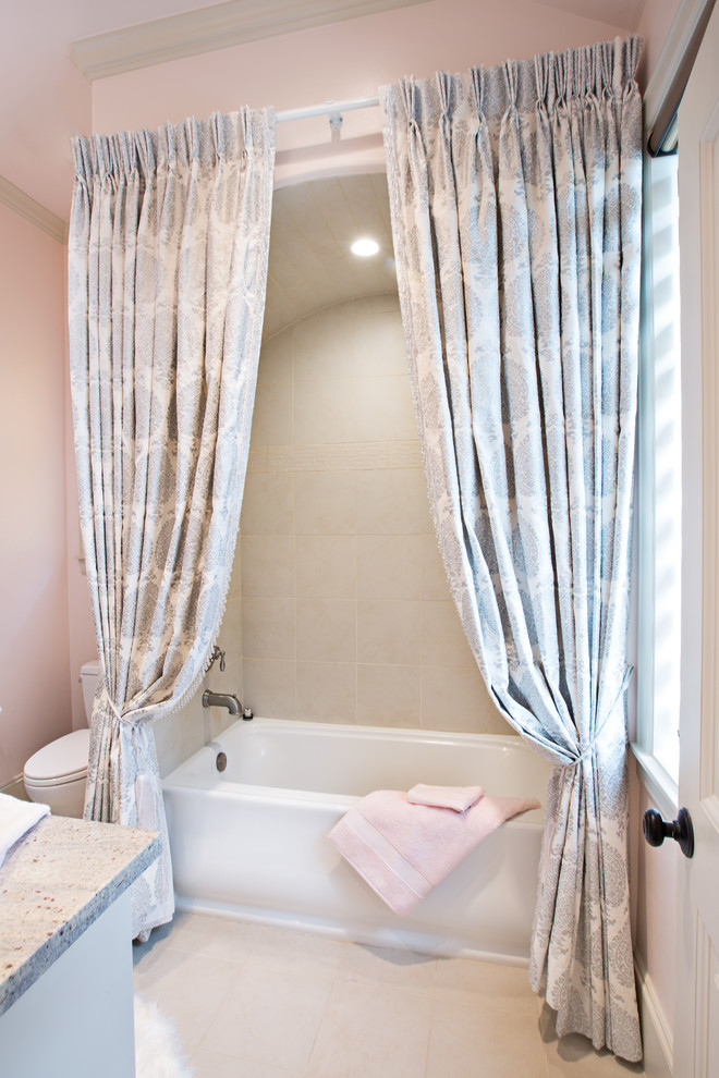 Bild på ett mellanstort vintage badrum för barn, med luckor med infälld panel, grå skåp, ett badkar i en alkov, en dusch/badkar-kombination, en toalettstol med hel cisternkåpa, grå kakel, stenkakel, rosa väggar, kalkstensgolv, ett undermonterad handfat och granitbänkskiva