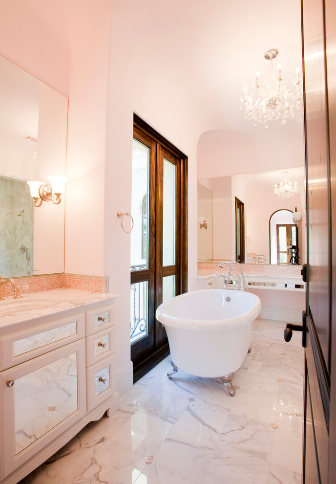 Klassisk inredning av ett mycket stort badrum för barn, med ett undermonterad handfat, luckor med glaspanel, marmorbänkskiva, ett badkar med tassar, en dusch/badkar-kombination, rosa kakel, mosaik, rosa väggar och marmorgolv