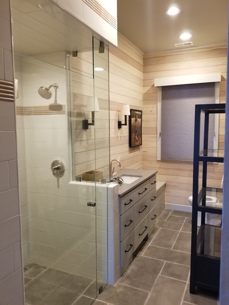 Example of a 1960s gray tile and limestone tile limestone floor and gray floor wet room design in Other with shaker cabinets, white cabinets, a one-piece toilet, white walls, an undermount sink, soapstone countertops and a hinged shower door