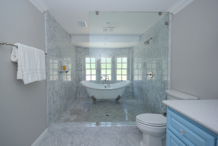 Klassisk inredning av ett stort en-suite badrum, med luckor med upphöjd panel, blå skåp, ett badkar med tassar, en öppen dusch, en toalettstol med hel cisternkåpa, vit kakel, porslinskakel, grå väggar, marmorgolv, ett nedsänkt handfat och bänkskiva i kvarts