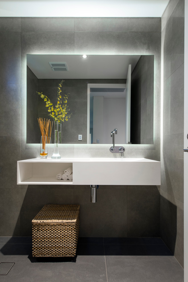 Cette photo montre une salle de bain tendance de taille moyenne avec un lavabo intégré, un placard sans porte, des portes de placard blanches et un carrelage gris.
