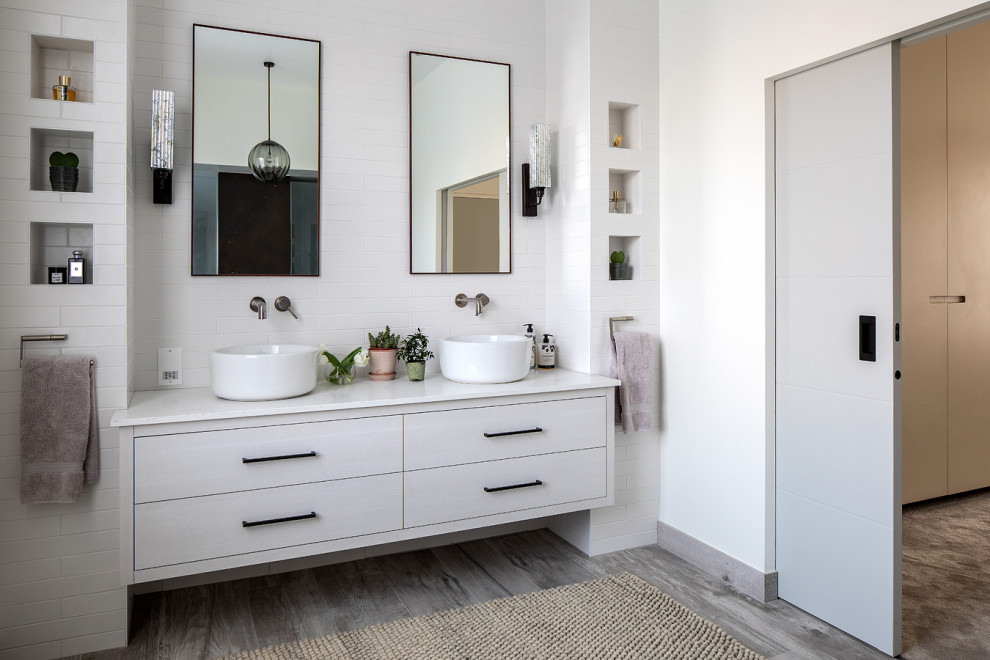 Photo of a contemporary bathroom in London with flat-panel cabinets, grey cabinets, white tiles, metro tiles, white walls, a vessel sink, grey floors, white worktops, double sinks and a floating vanity unit.