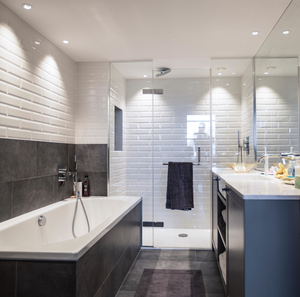 This is an example of a medium sized industrial ensuite bathroom in London with shaker cabinets, a built-in bath, a built-in shower, a wall mounted toilet, white tiles, ceramic tiles, grey walls, ceramic flooring, a built-in sink and marble worktops.