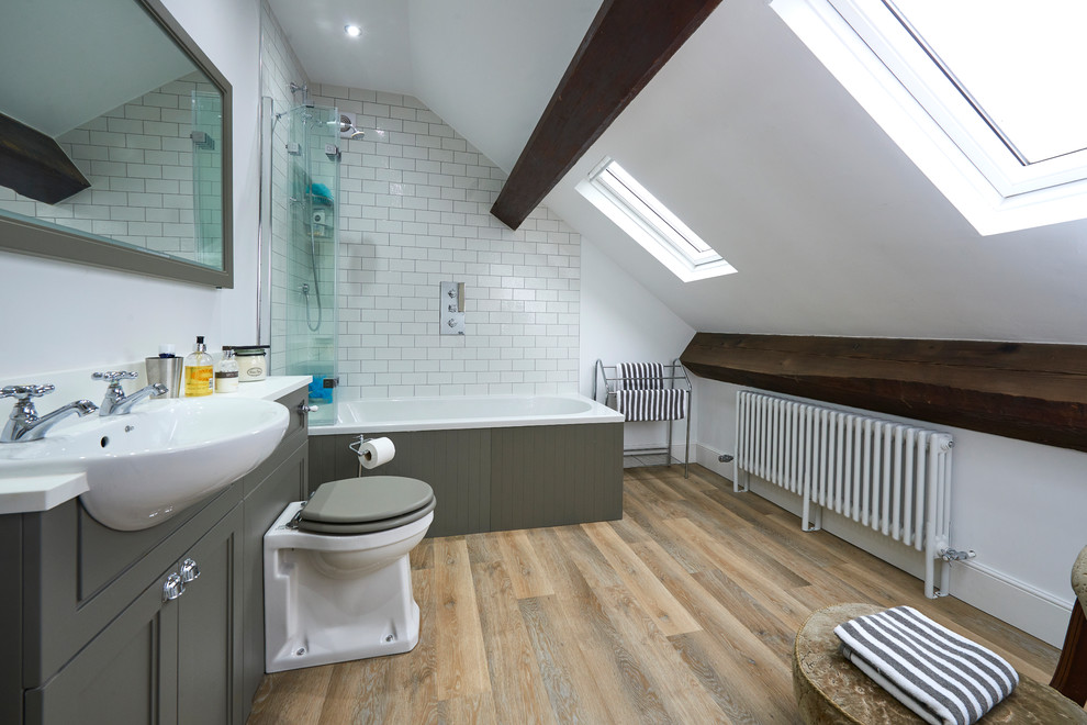 Traditional ensuite bathroom in Other with recessed-panel cabinets, grey cabinets, a built-in bath, a shower/bath combination, metro tiles, white walls, medium hardwood flooring, a built-in sink, brown floors, an open shower and white worktops.
