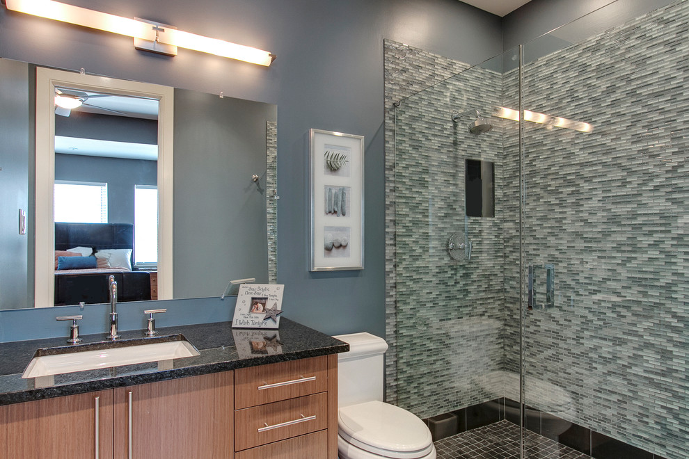 Bild på ett mellanstort funkis badrum med dusch, med släta luckor, skåp i ljust trä, en dusch i en alkov, en toalettstol med separat cisternkåpa, grön kakel, vit kakel, stickkakel, grå väggar, ett undermonterad handfat och granitbänkskiva