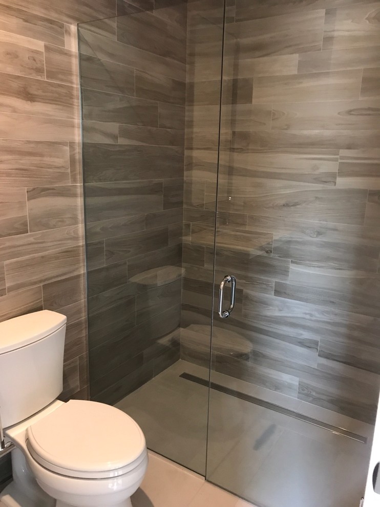 Example of a mid-sized trendy 3/4 brown tile and porcelain tile ceramic tile and beige floor walk-in shower design in Las Vegas with a two-piece toilet and a hinged shower door