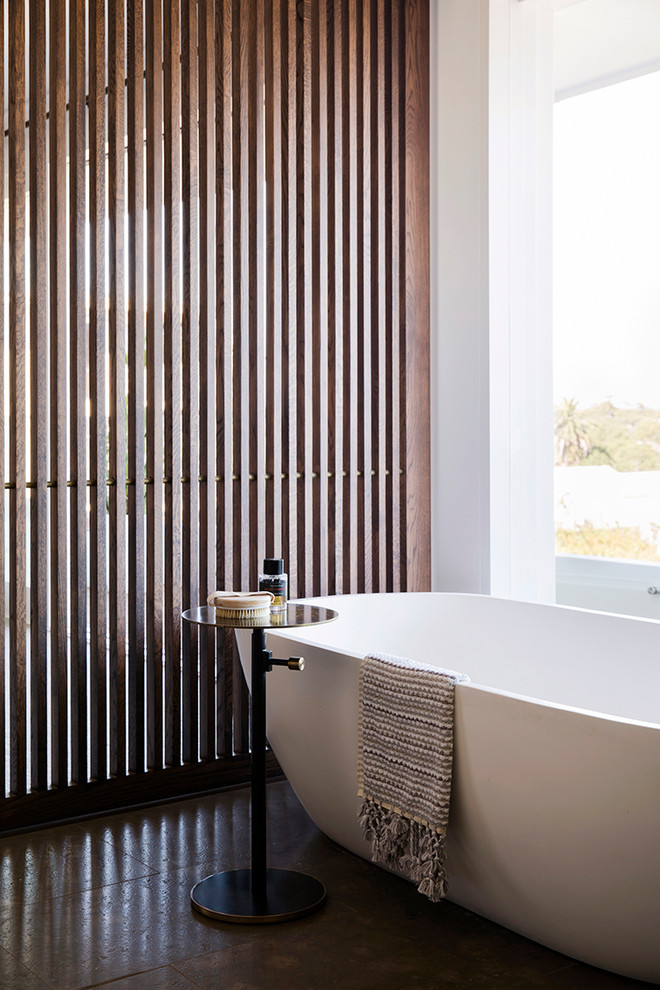 Diseño de cuarto de baño contemporáneo con bañera exenta, paredes blancas y suelo marrón