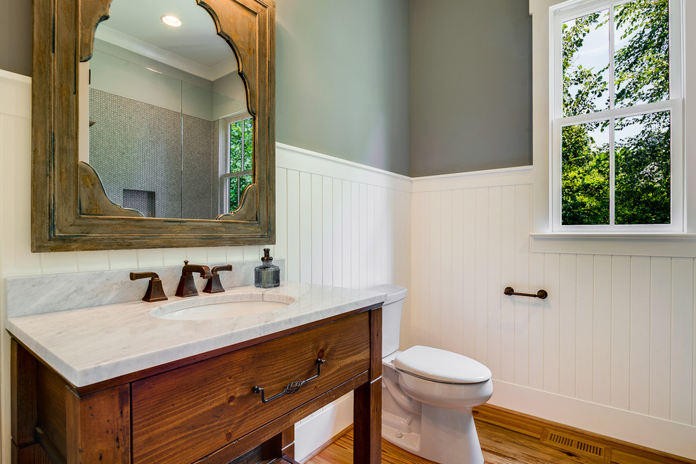 シャーロットにあるカントリー風のおしゃれな浴室 (アンダーカウンター洗面器、中間色木目調キャビネット、緑の壁、無垢フローリング、分離型トイレ、フラットパネル扉のキャビネット) の写真