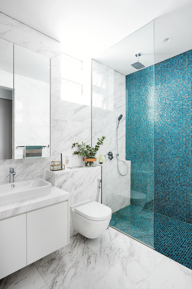 Example of a trendy blue tile, white tile and mosaic tile marble floor walk-in shower design in Singapore with flat-panel cabinets, white cabinets, a wall-mount toilet and a vessel sink
