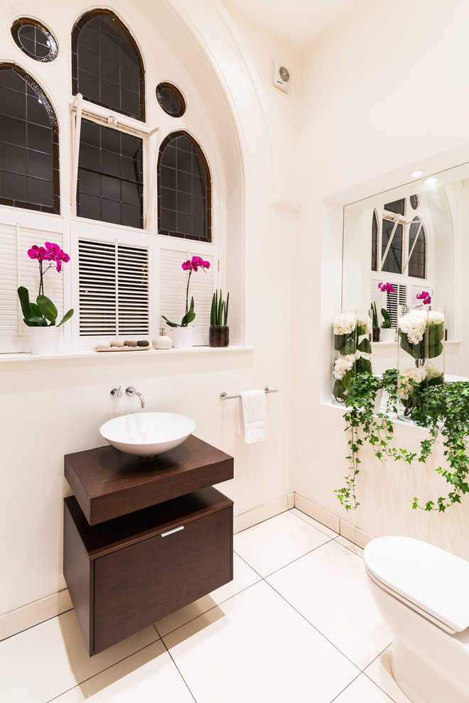 Medium sized contemporary ensuite bathroom in London with dark wood cabinets, a freestanding bath, a one-piece toilet, white tiles, ceramic tiles, white walls, ceramic flooring, a pedestal sink, wooden worktops and flat-panel cabinets.