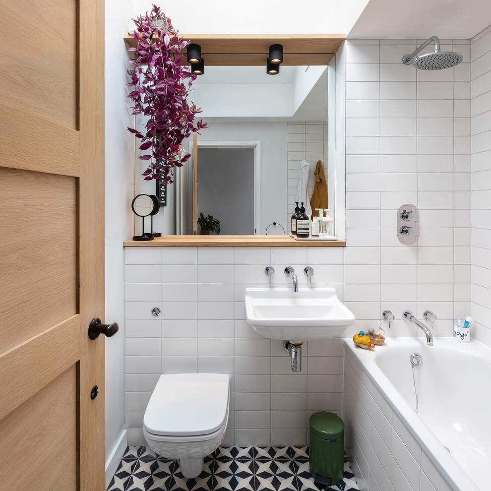 Idee per una piccola stanza da bagno con doccia design con vasca ad alcova, vasca/doccia, WC sospeso, piastrelle bianche, pareti bianche, lavabo sospeso, pavimento multicolore e doccia aperta