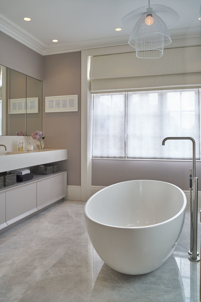 Imagen de cuarto de baño infantil tradicional renovado con puertas de armario grises, bañera exenta, paredes grises, suelo de mármol y encimera de madera