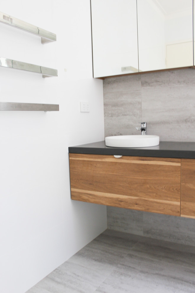 Small modern shower room bathroom in Perth with flat-panel cabinets, dark wood cabinets, a walk-in shower, a one-piece toilet, grey tiles, porcelain tiles, white walls, porcelain flooring, a vessel sink, engineered stone worktops, grey floors, an open shower and black worktops.