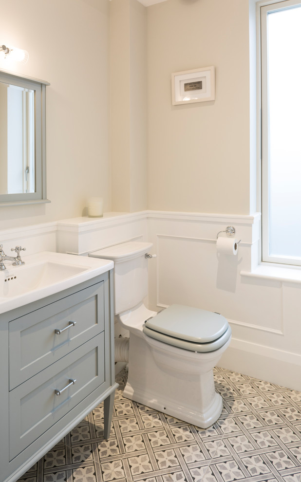 Aménagement d'une petite salle de bain classique pour enfant avec un placard avec porte à panneau encastré, des portes de placard grises, WC à poser, un mur beige, carreaux de ciment au sol et un sol gris.