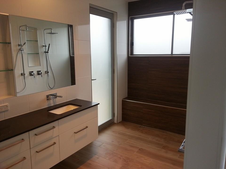 Modelo de cuarto de baño contemporáneo con lavabo bajoencimera, encimera de cuarzo compacto, ducha doble, baldosas y/o azulejos marrones, paredes blancas y suelo de baldosas de porcelana